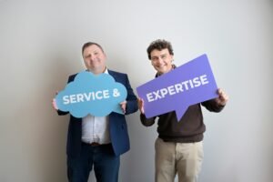 Deux personnes présentant des panneaux détaillant leurs services et expertises.