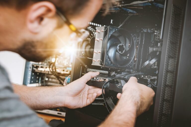 Technicien réparant le ventilateur d'un ordinateur : jeune homme connectant un nouveau composant au processeur.